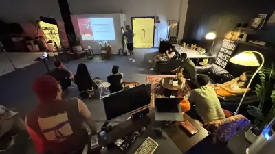 A wide view of filmmakers and creatives gathered around the projector for Tim Ramak’s storytelling lesson at The A Frame.